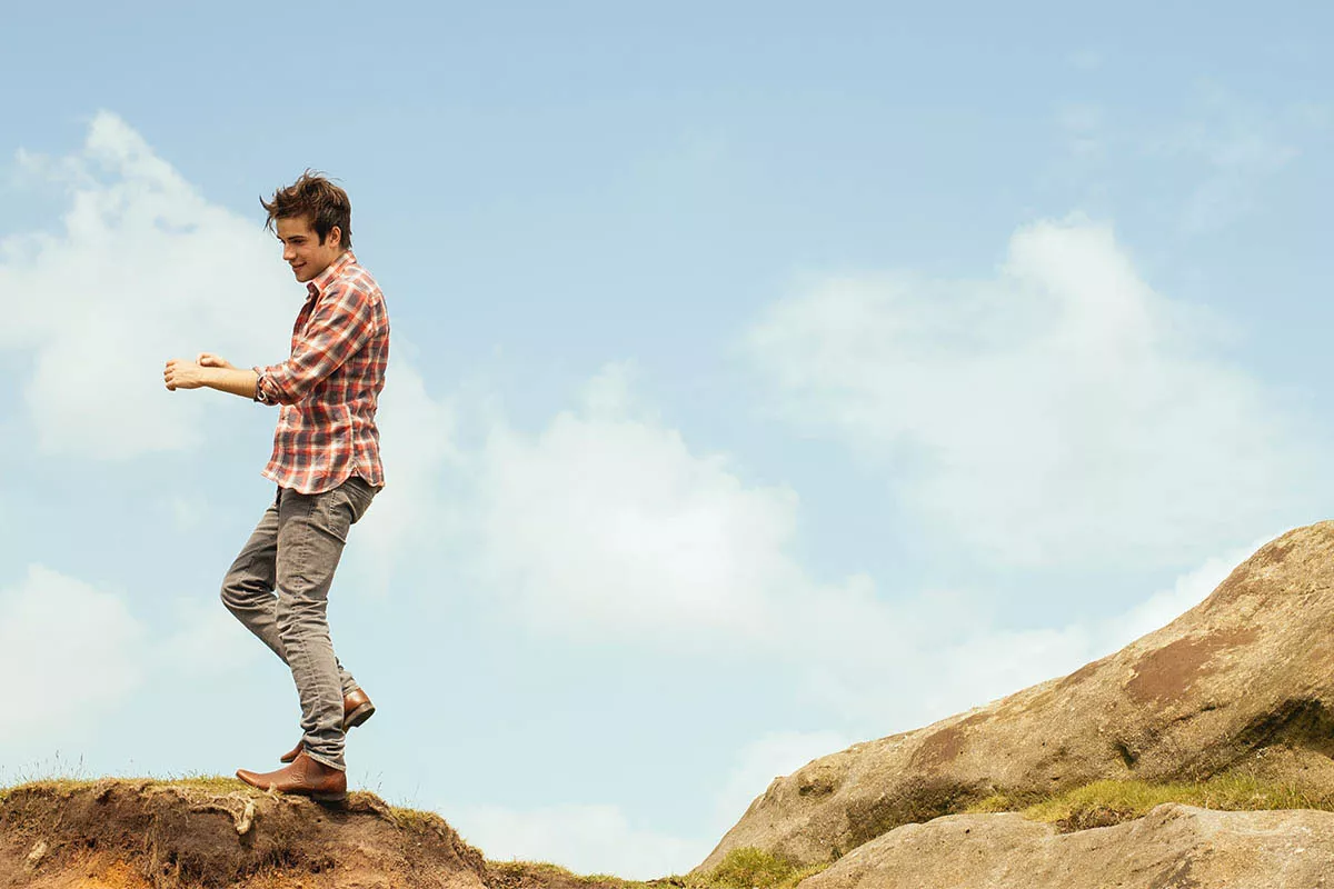 Junger Mann balanciert auf einem Berg